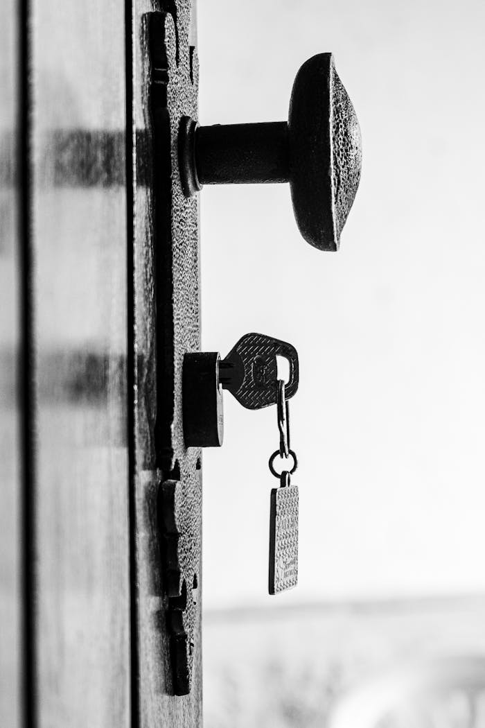 Close-up of a key in an antique lock on a rustic door, black and white.