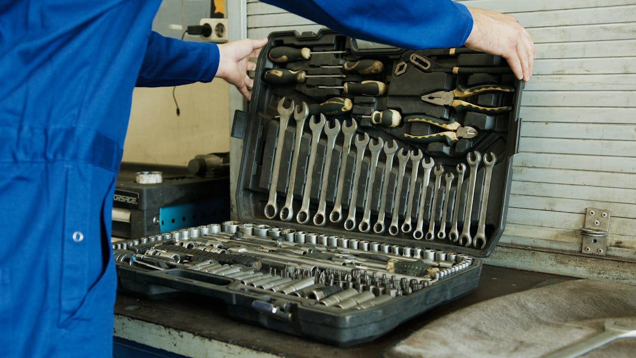 Mechanic organizing a comprehensive tool set for vehicle maintenance in a workshop setting.